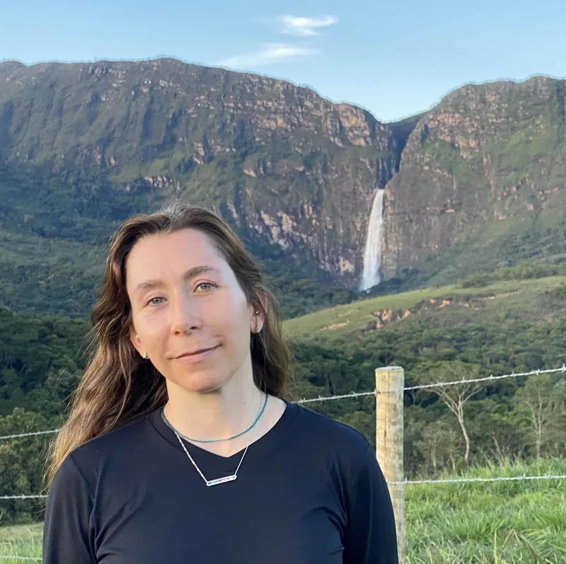 Diana Procopio Roger, teacher of Brazilian Portuguese, standing in front of a mountain waterfall in Brazil
